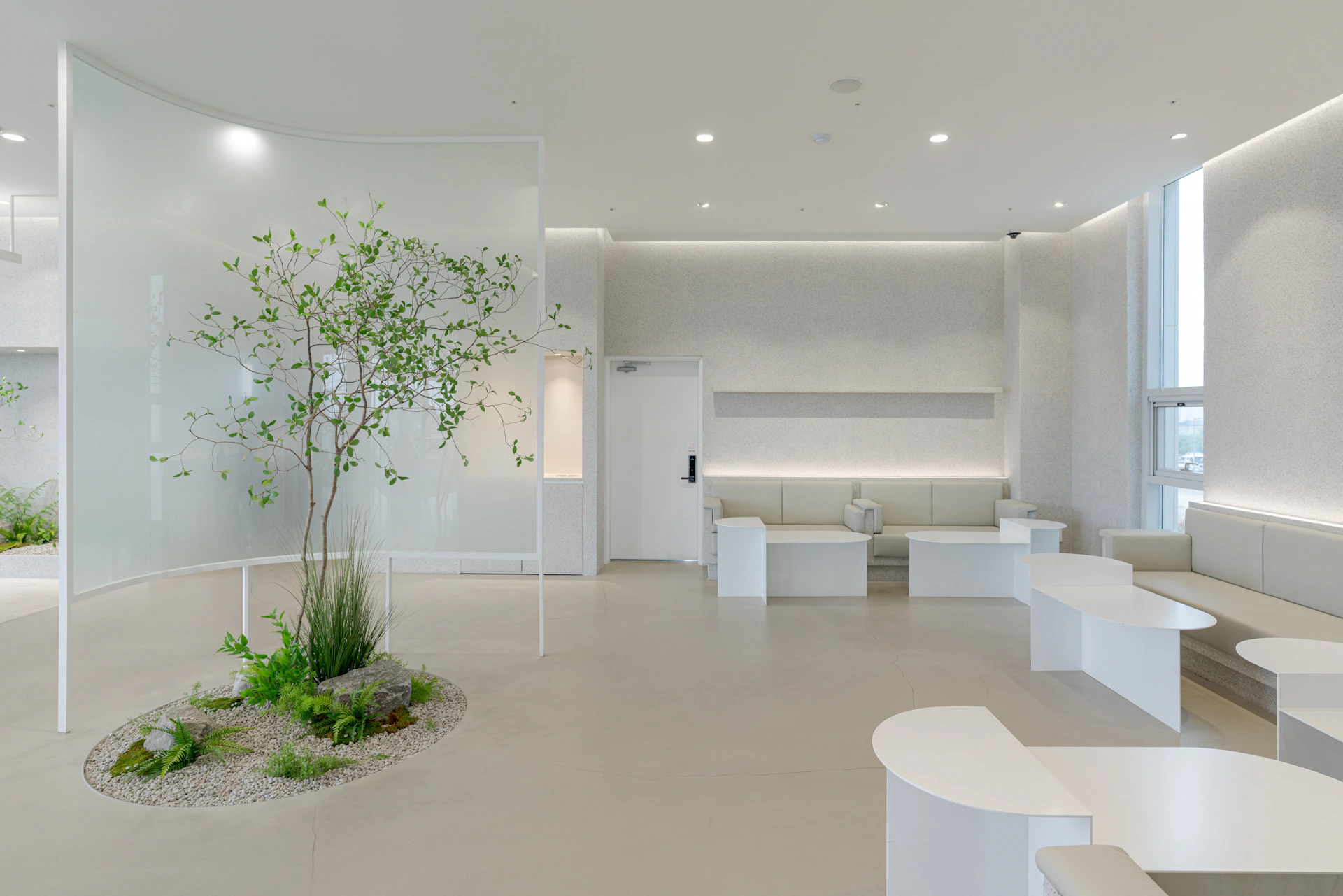 Interior de la clínica NOVA: lounge de espera con luz natural, mármol travertino y jardín interior circular